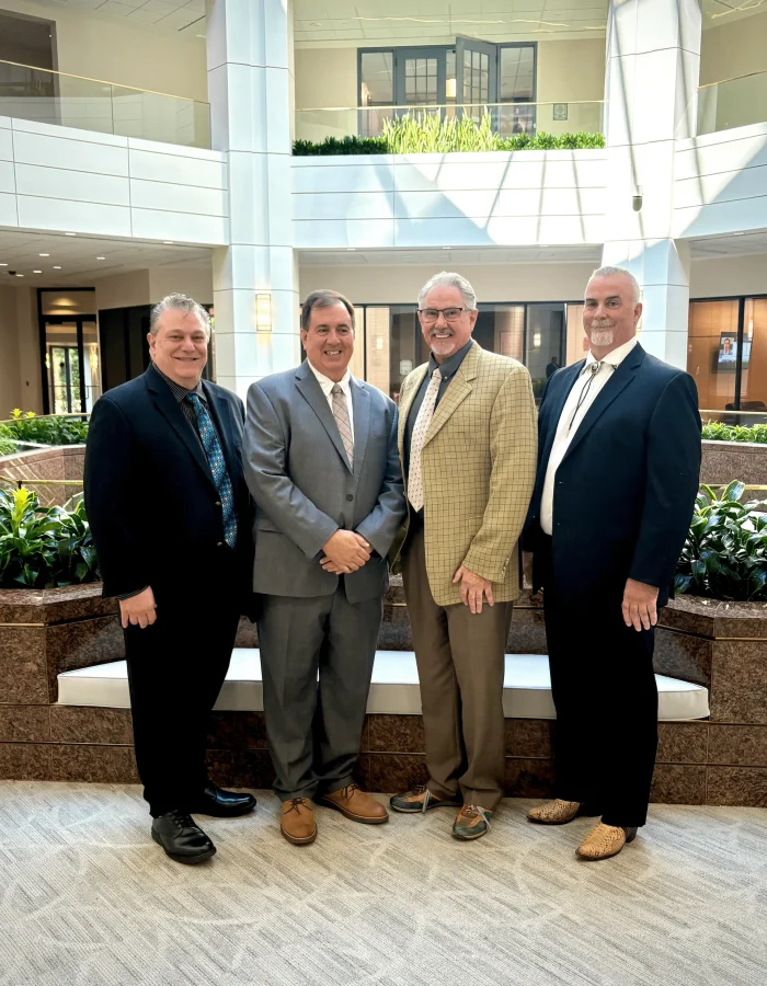 Four members of the MAST Sales Group team standing together in an office atrium